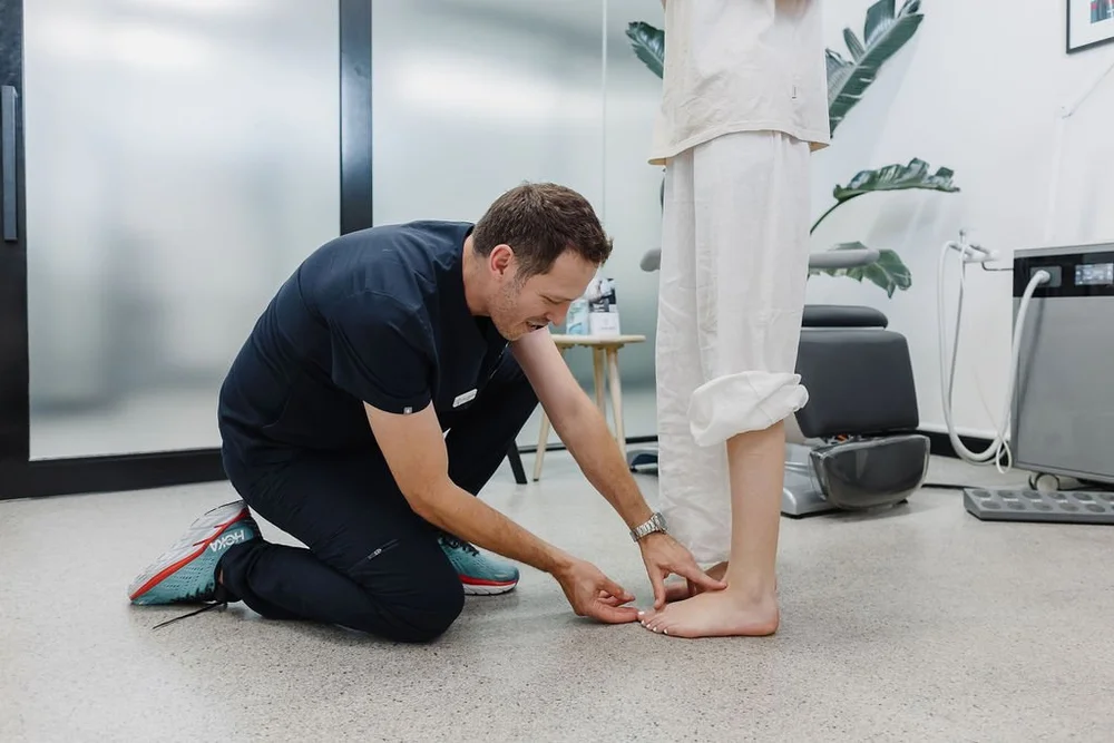 A podiatrist examining a patient's foot and ankle in standing