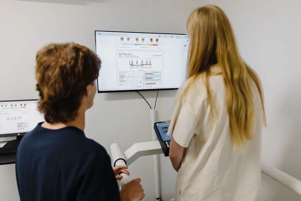 A podiatrist and patient reviewing gait analysis results on screen