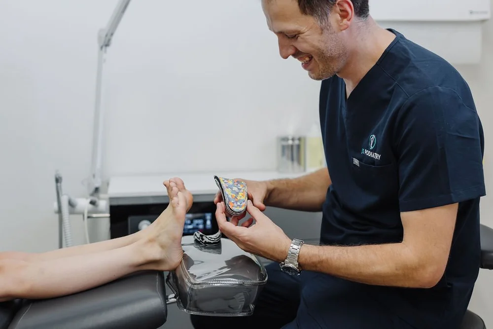 A podiatrist showing a patient an orthotic device in the clinic