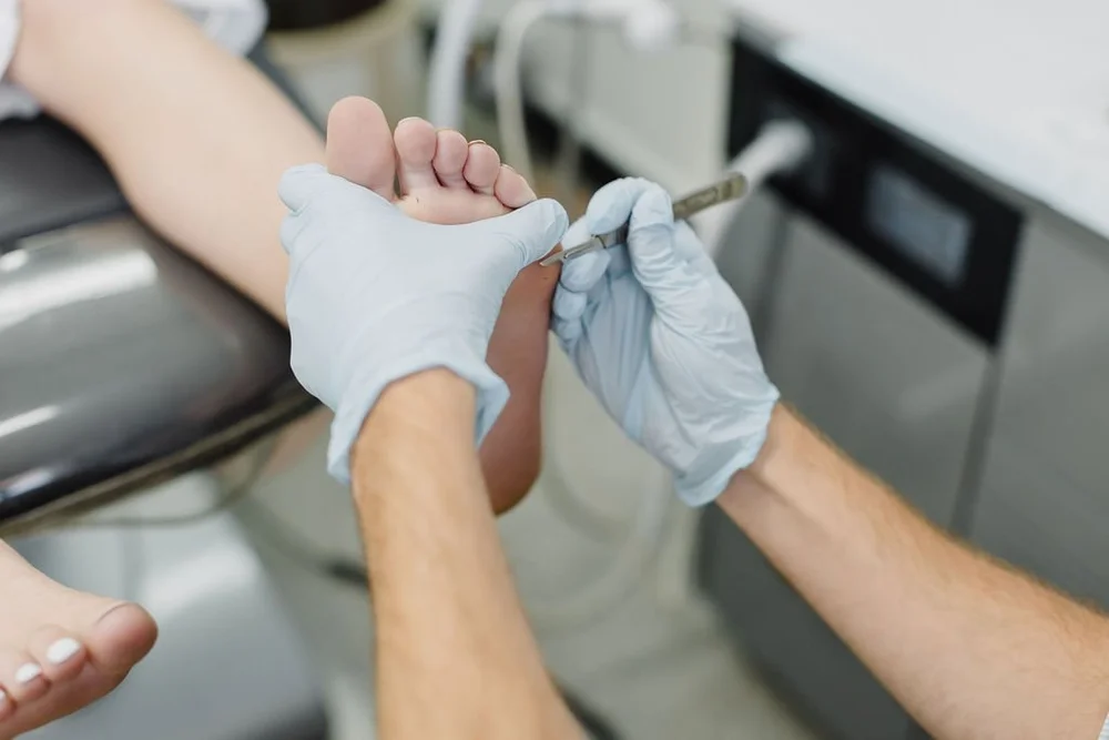 A podiatrist treating the edge of a toenail with a sterile instrument