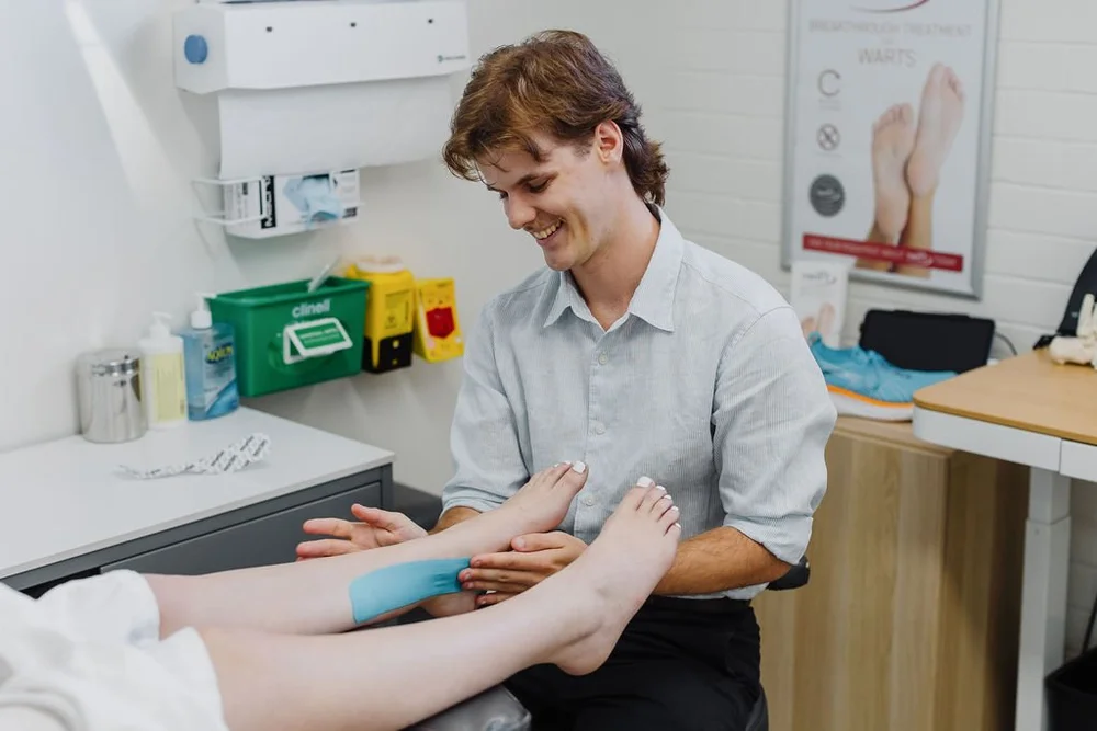 A podiatrist applying strapping tape to a patient's foot and ankle