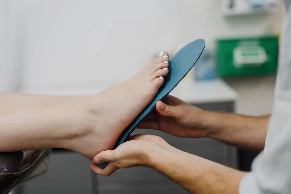 A 3D printed custom orthotic being checked against a patient's foot
