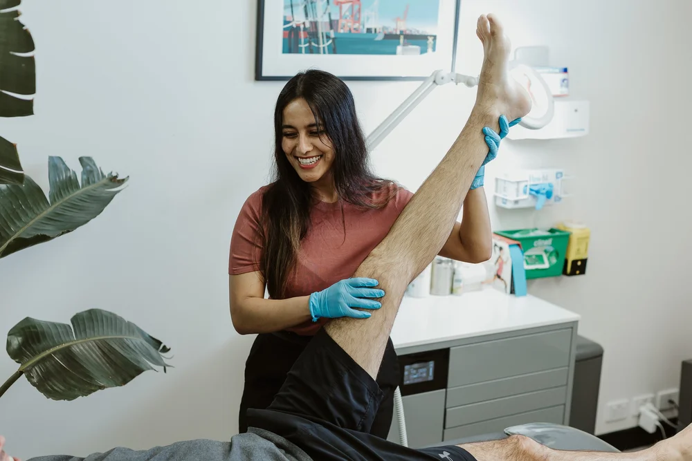 A podiatrist holding a patient's leg with supportive tape applied to the foot
