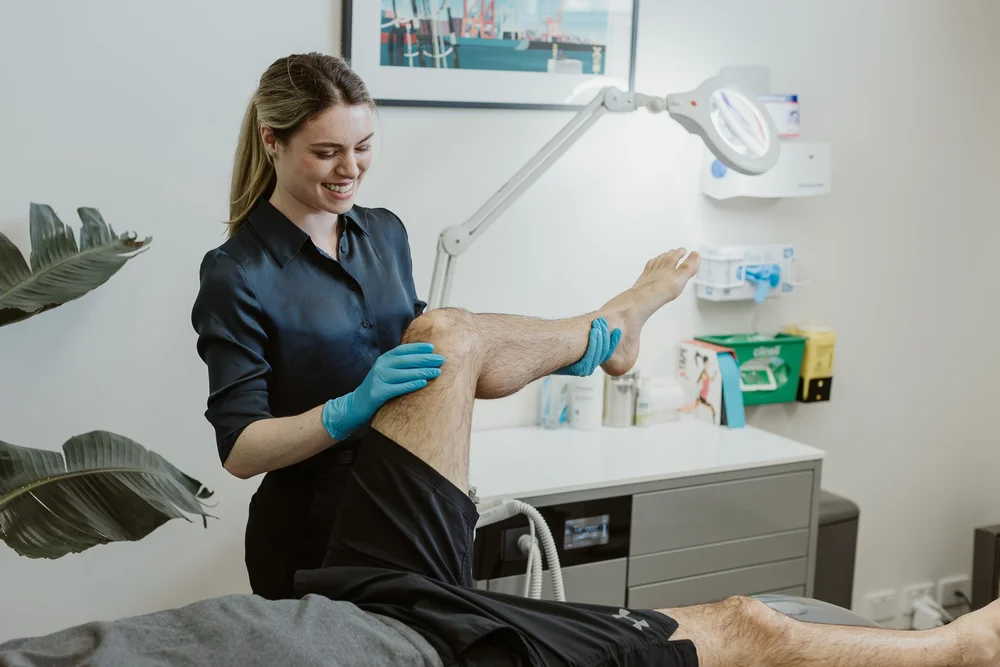 A podiatrist supporting a patient's ankle with strapping tape applied
