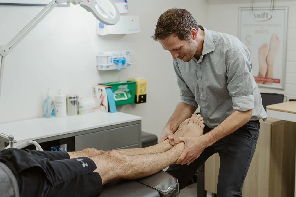 A podiatrist moving a patient's foot and ankle through its range during an assessment