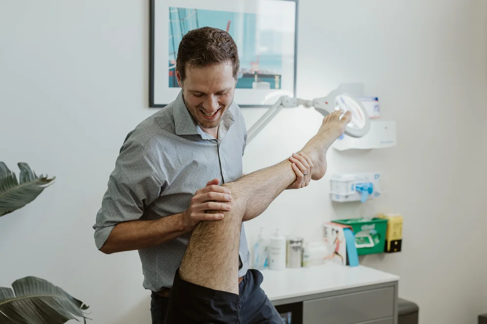 A podiatrist examining a patient's lower leg and foot under the clinic lamp