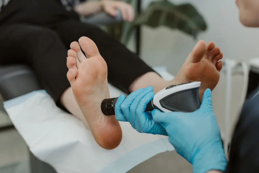 A handheld treatment device applied to the sole of a patient's foot