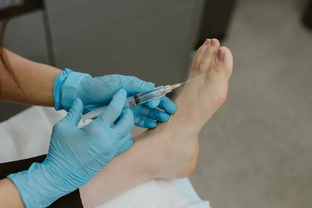 A podiatrist delivering an injection to the forefoot