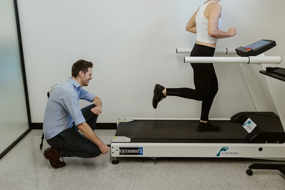 A podiatrist watching a patient run on the treadmill during an assessment