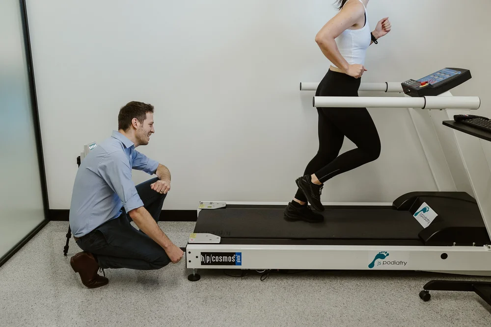 A podiatrist watching a runner on the treadmill during a running assessment