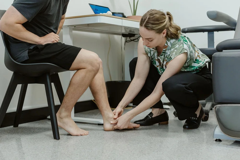 A podiatrist examining the heel and arch of a seated patient